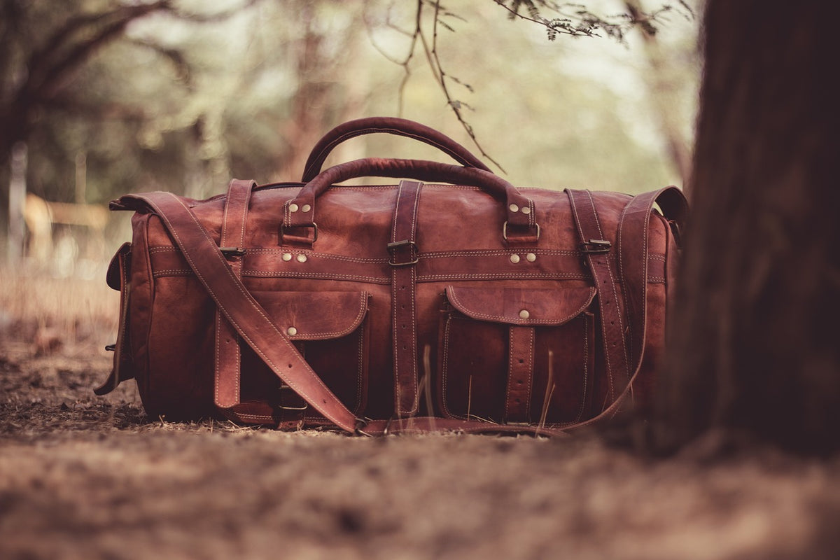 Full-grain leather weekender bag resting on a path